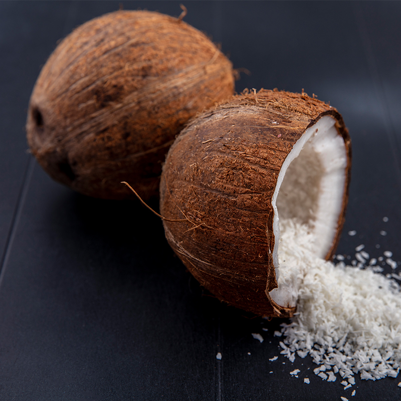 Desicated coconut Close-up of desiccated coconut on a white background, displaying fine, dry flakes of coconut meat with a light beige color. The flakes are small and appear to be grated or shredded, commonly used as a topping or ingredient in various culinary dishes.