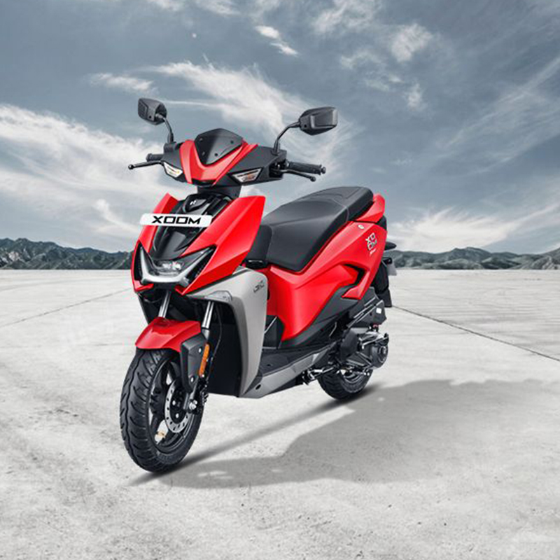 front-left-view-1084036401_930x620 The scooter features a modern and minimalist design with a clean silhouette, sharp lines, and LED lighting. It has a compact body, with a digital instrument cluster, disc brakes, and alloy wheels. The scooter is powered by an electric motor and has a removable Lithium-Ion battery, offering a range of up to 75 km per charge. It also has regenerative braking for enhanced energy efficiency. The alt text highlights the scooter's contemporary design, electric powertrain, and eco-friendly features.