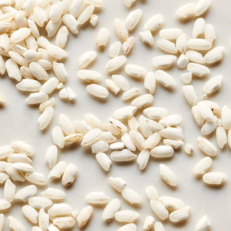 Arborio Rice_ Arborio rice grains are medium in size and have a pearly white color. The image may show a pile of uncooked Arborio rice grains or a cooked dish of creamy risotto made with Arborio rice.