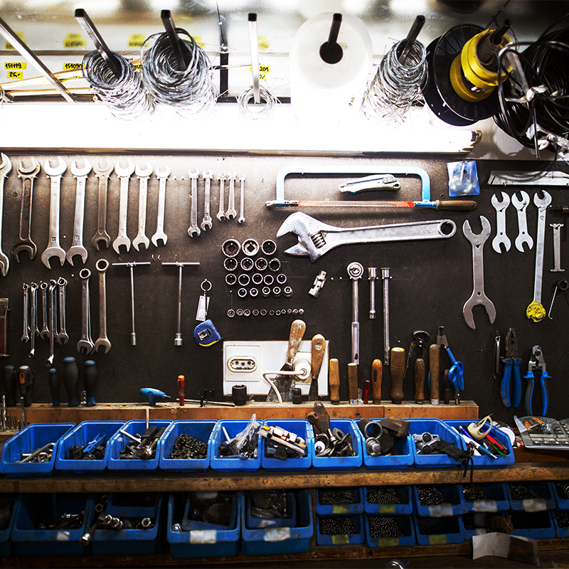 Garage Tools The tools include wrenches, sockets, pliers, screwdrivers, hammers, and other hand tools. The tools are laid out neatly on a workbench, with some tools hanging on a pegboard in the background.