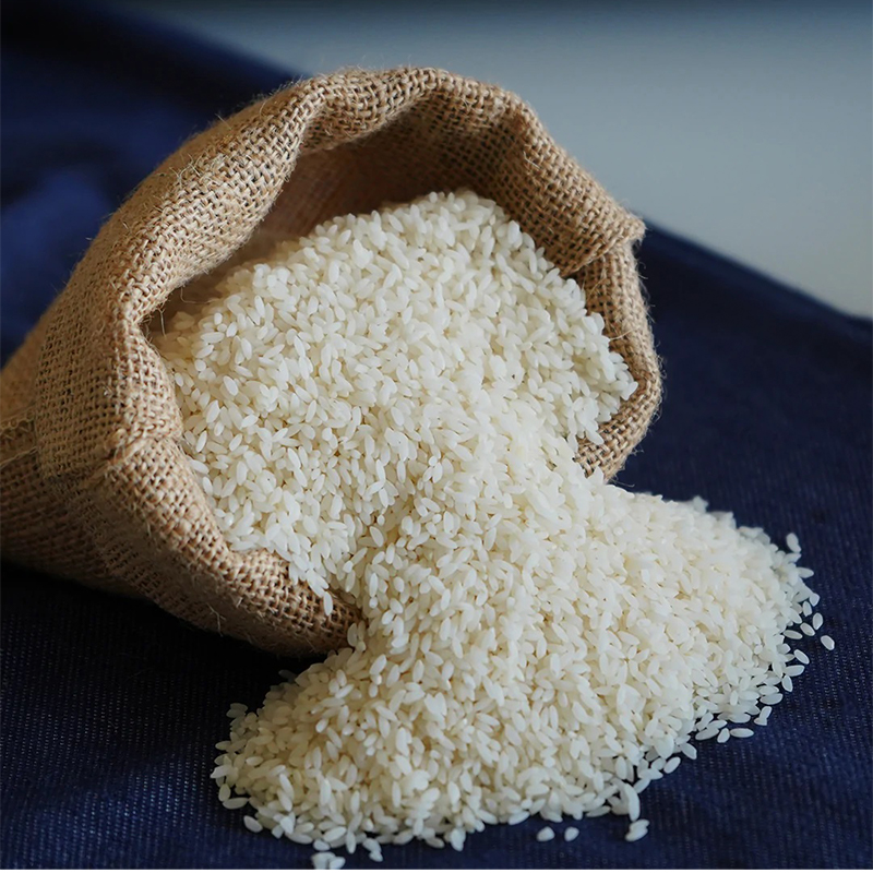 Gobindobhog The grains of Gobindobhog rice are short and plump, with a golden-yellow color. The image may show a bowl of cooked Gobindobhog rice or a pile of uncooked rice grains. Gobindobhog rice is known for its distinct aroma and sweet flavor, often compared to the fragrance of jasmine flowers.