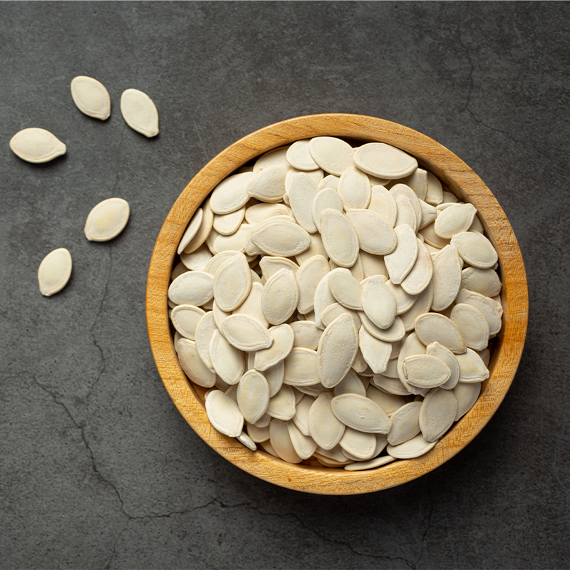 Pumpkin Seeds The pumpkin seeds are small and flat with a teardrop shape, and have a light brown color with a slightly glossy surface. The image captures the appearance of pumpkin seeds, a popular snack and ingredient in various dishes known for their mild, nutty flavor and crunchy texture. The alt text conveys the small, flat teardrop shape, light brown color, and glossy surface of pumpkin seeds. Pumpkin seeds can be eaten on their own as a snack or used as a topping for salads, yogurt, or oatmeal.