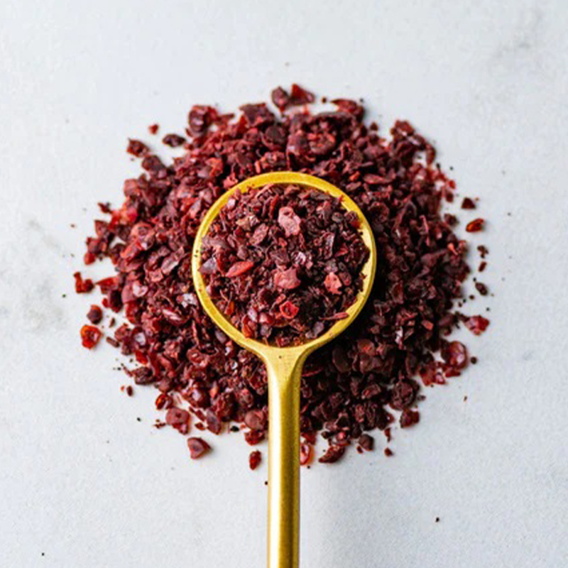 Sumac The powder is deep red in color and has a fine texture. The image captures the appearance of Sumac, a spice commonly used in Middle Eastern cuisine. The alt text conveys the deep red color and fine texture of Sumac powder. Sumac has a tangy and slightly sour taste, and is often used as a seasoning for meat, fish, vegetables, and salads.