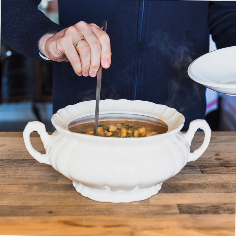 Soup toureen A ceramic soup tureen with lid and ladle, filled with delicious and steaming soup.